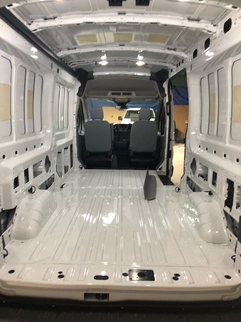 Inside of an empty white van, showing the interior with seats in the front.