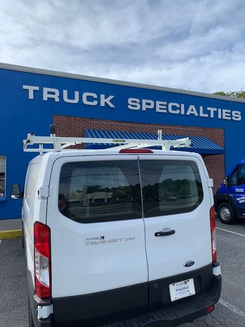 White van with roof rack parked in front of a blue 