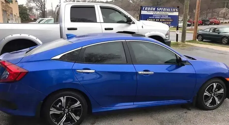 Blue Honda Civic sedan parked next to a silver pickup truck; outdoors.