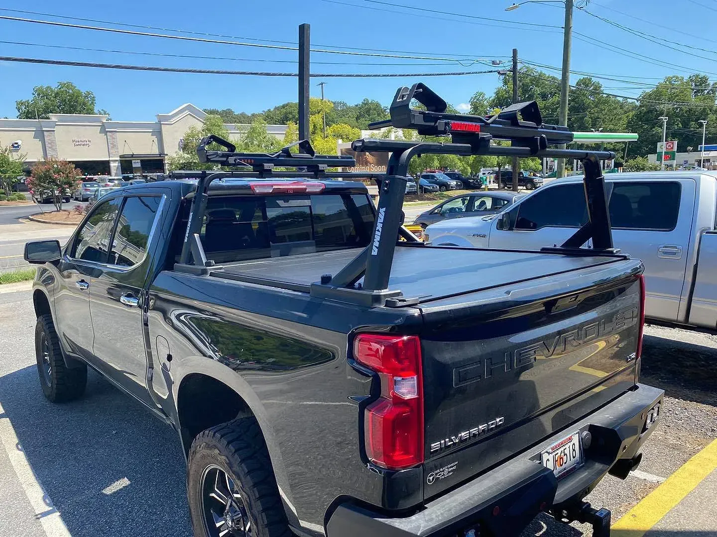 Black pickup truck with a rack and bike carrier, parked outdoors.