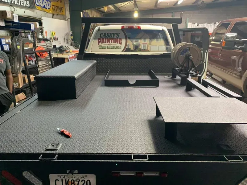 Flatbed truck with toolboxes and welding equipment in a shop.