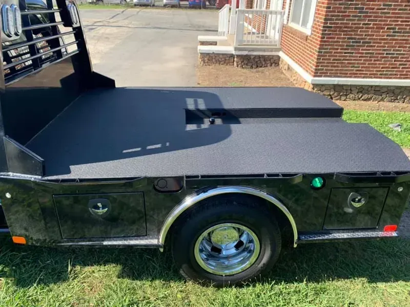 Black flatbed truck with chrome wheels and storage compartments.