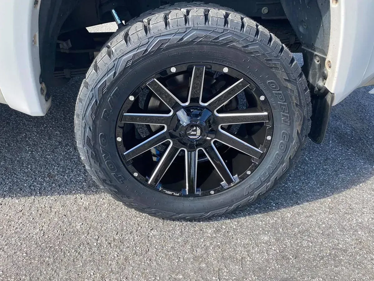 Black and white wheel on a vehicle, showing a tire with a rugged tread pattern.