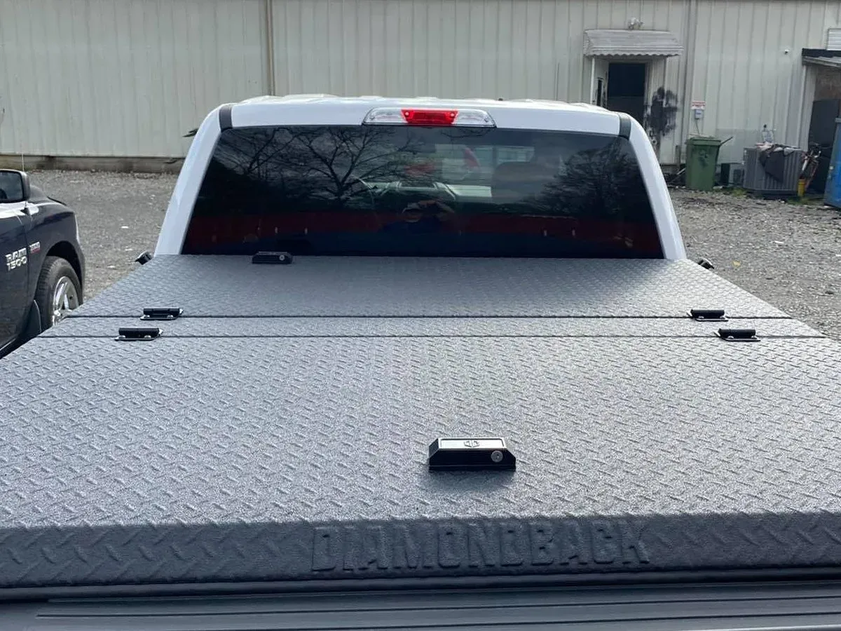 Rear view of a white pickup truck with a diamond plate tonneau cover.