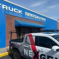 Truck Specialties building with a white truck parked in front. The truck has the NEXGEN logo.
