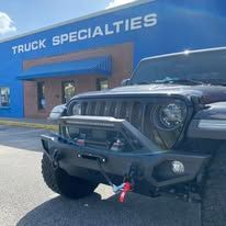 Black truck parked in front of a blue building that says