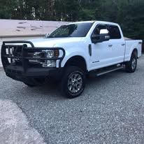 White pickup truck parked on asphalt. Black grill guard on front.