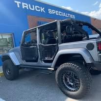 A modified grey truck with large black wheels parked outside of