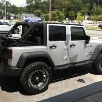 Silver Jeep with black soft top parked outdoors.