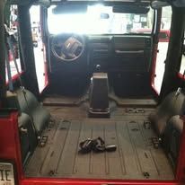Interior of a red Jeep. Empty passenger area with the front dashboard visible, no seats.
