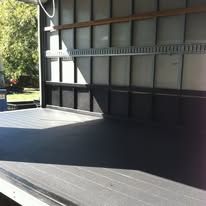 Empty truck interior; dark gray floor, metal tie-down rails on walls.