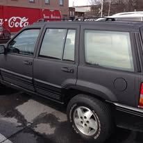 Dark gray SUV parked outside a building with a Coca-Cola sign.