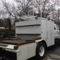 White utility truck with equipment storage, outdoors.