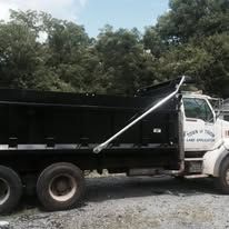 Black dump truck with a white cab, parked outdoors.
