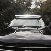 Black car with a bright LED light bar mounted above the windshield.