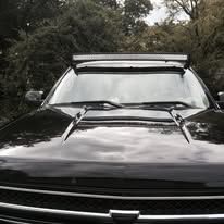 Black truck with light bar on the hood, outdoors.