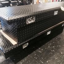 Black diamond plate truck toolboxes stacked on a shiny floor.