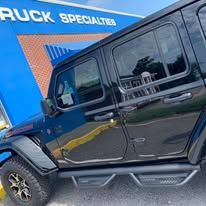 Black Jeep parked outside a business with a blue sign.