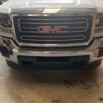 Close-up of a silver GMC truck front grille, with the GMC logo in red.