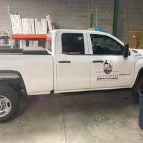 White pickup truck with company logo parked inside a warehouse.