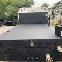 Black flatbed truck with gray platform, outdoor setting.
