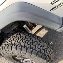 Close-up of a black tire on a white Jeep Wrangler Unlimited.