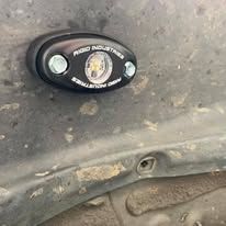 Black Rigid Industries LED rock light mounted on a car's undercarriage.