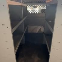 Empty, light-colored storage shelving, viewed from inside. White cloth sits on the middle shelf.