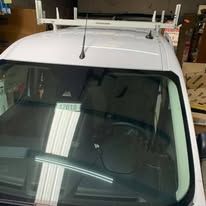 White van with ladder rack on roof; windshield view.