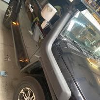 Black Jeep with a snorkel, showing side view of the front end.