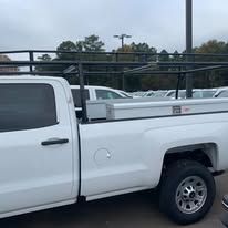 White truck with black ladder rack, outdoors.