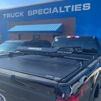 Black truck with a truck bed cover parked in front of a