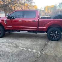 Red pickup truck with black wheels parked outside on concrete.