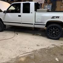 White pickup truck with black wheels parked outside.