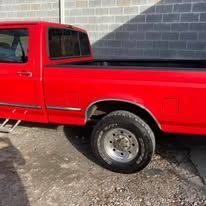 Red pickup truck parked near a gray brick wall.