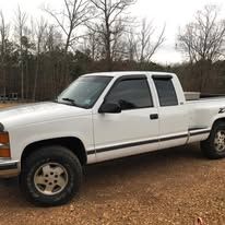 White pickup truck parked outdoors on a dirt surface.