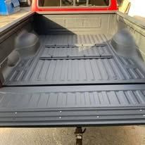 Black truck bed, view from the top down. Empty, clean, and textured with horizontal ribs.