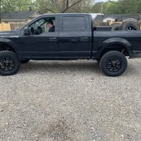 Black pickup truck parked on gravel.