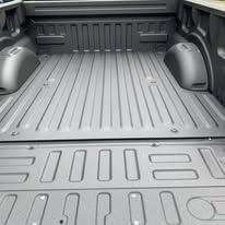 Gray truck bed with textured lining and ribbed floor.