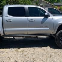 Silver pickup truck with black side steps, parked outdoors.