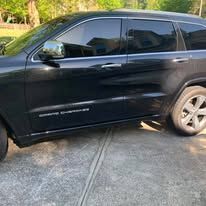 Black Jeep Cherokee parked on a sunny paved surface.