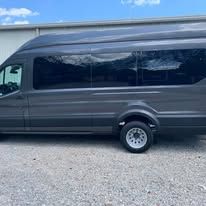 Gray passenger van parked outdoors with tinted windows.