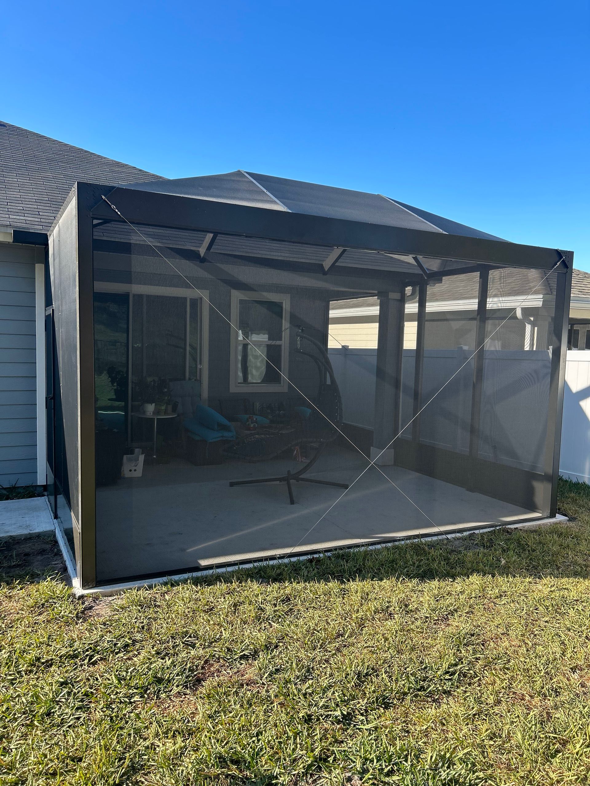 A screened in porch in the backyard of a house.