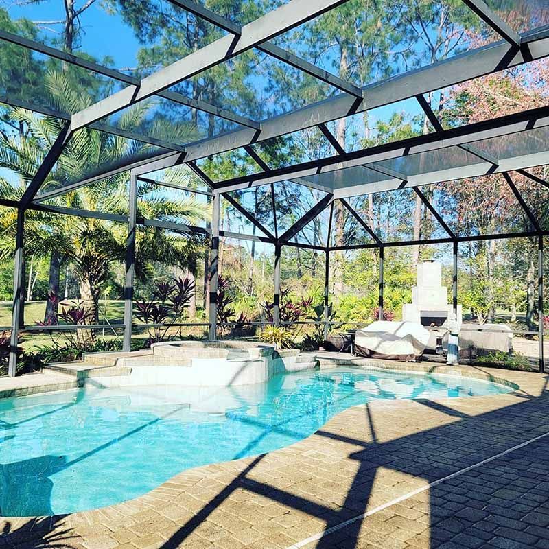 A large swimming pool is covered in a screened in area.