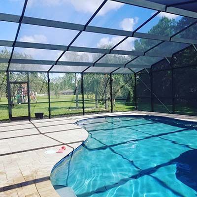 A swimming pool inside of a screened in area