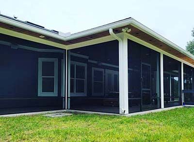 A screened in porch on the side of a house.
