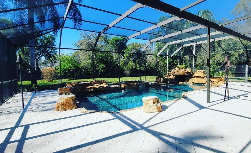 There is a swimming pool in the backyard with a screened in area.