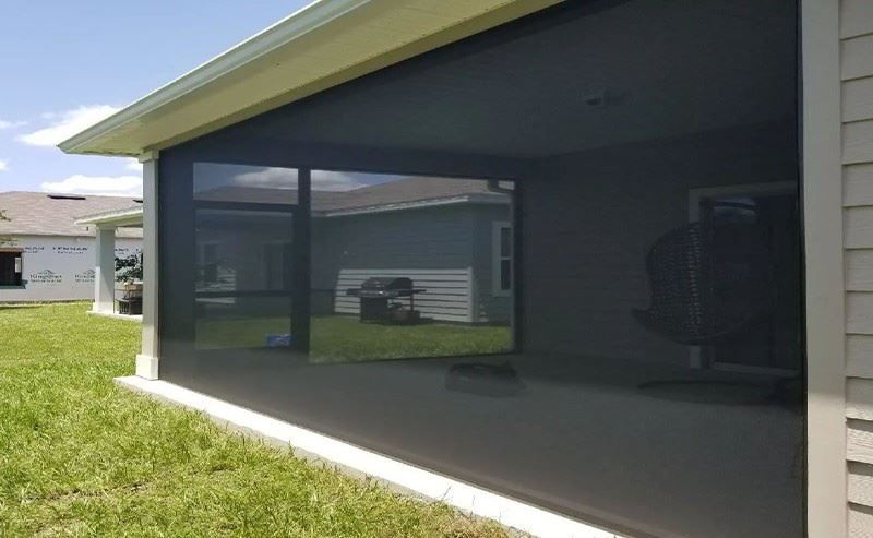 A screened in porch with a black screen on the side of a house.