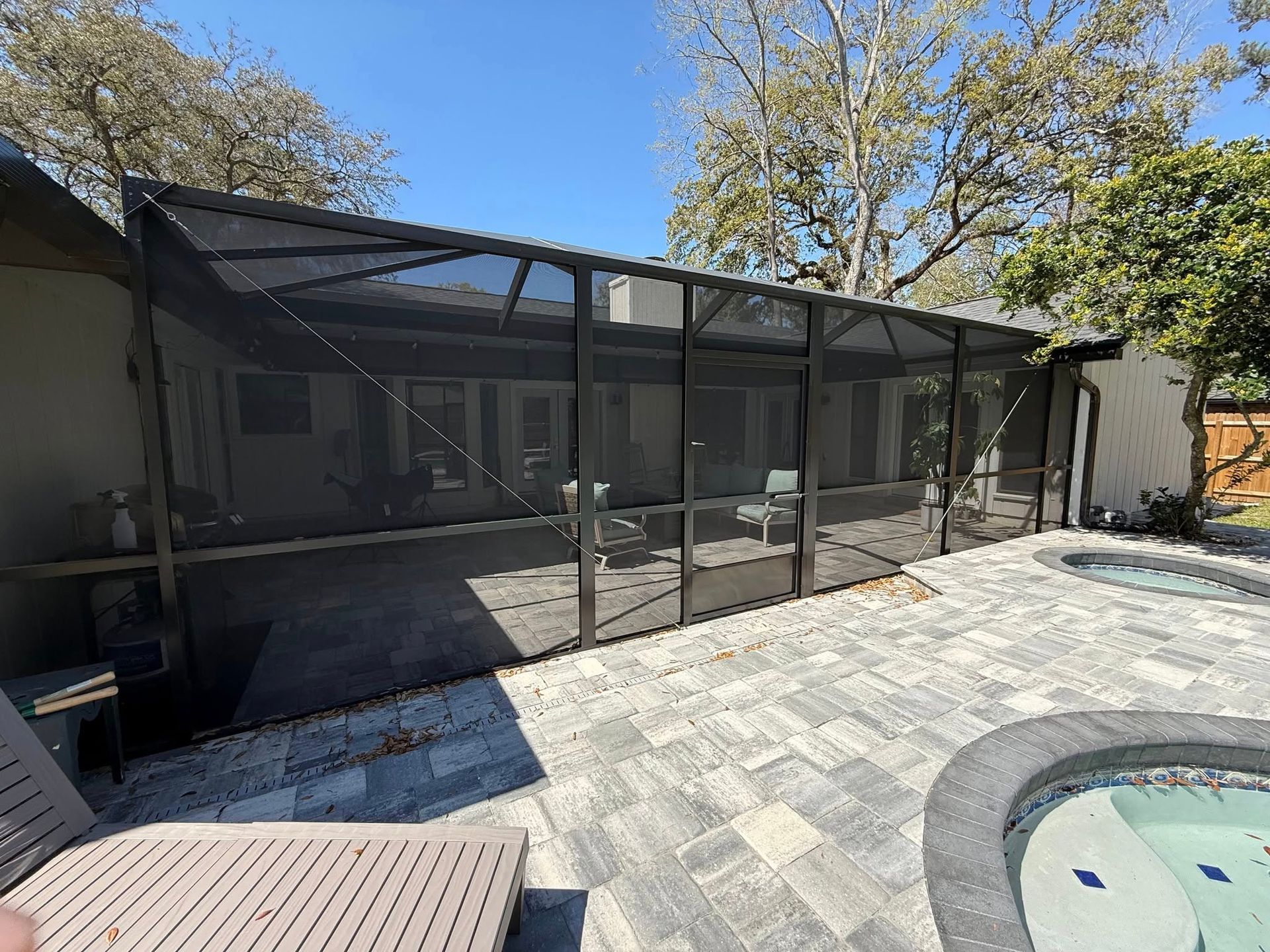 A screened in porch next to a swimming pool.