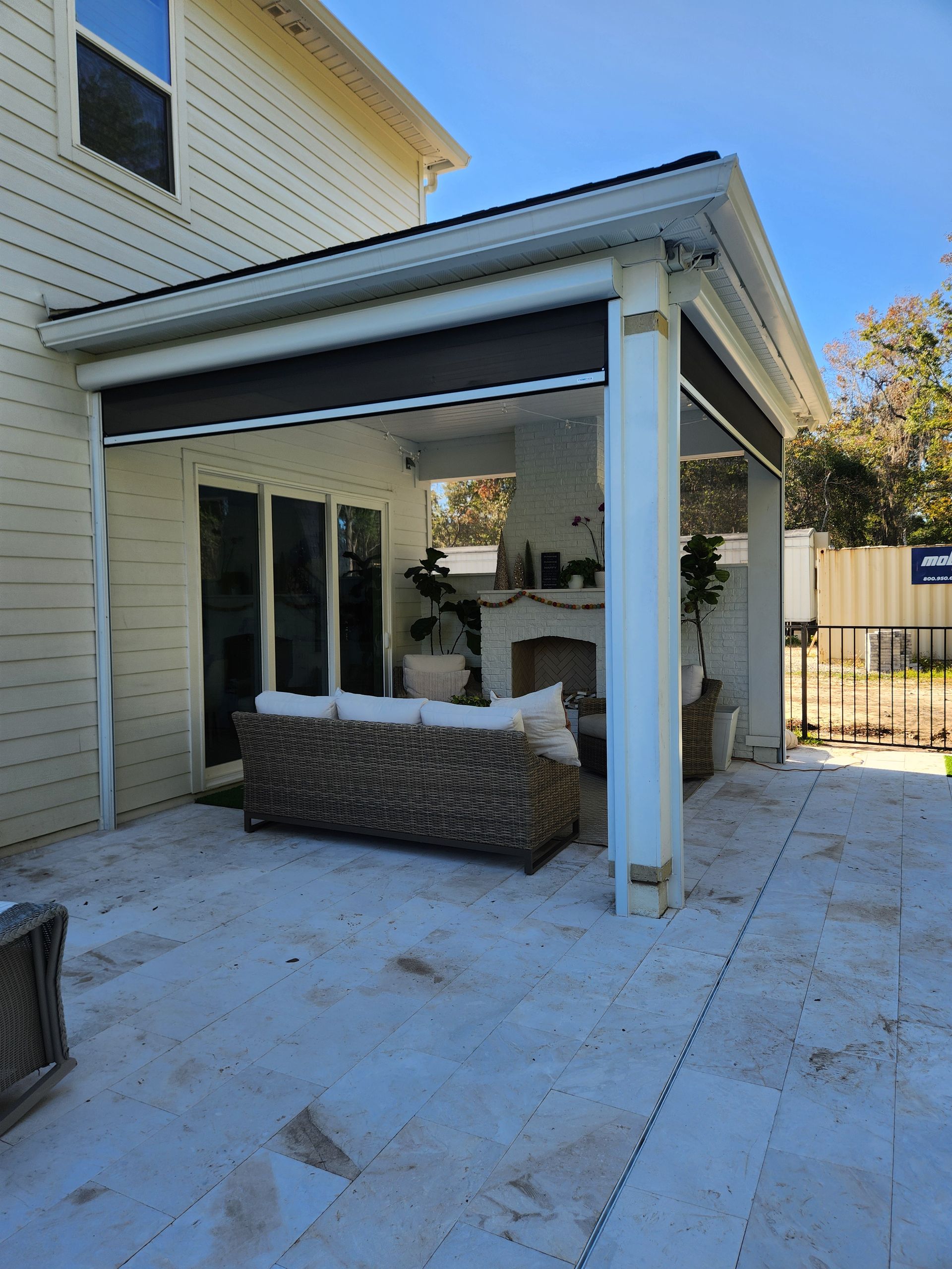 A patio with a couch and a fireplace in front of a house
